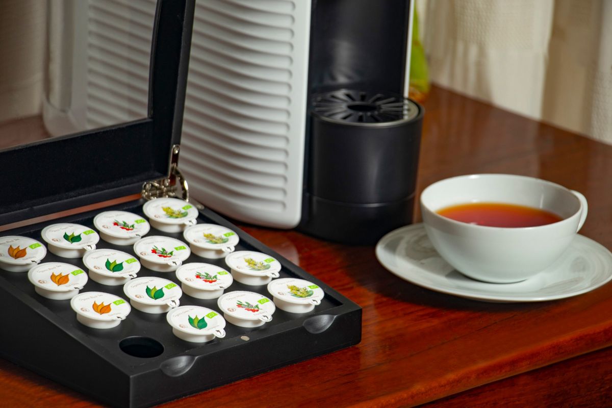 Caja de cápsulas de té Bistrotea junto a una máquina y una taza
