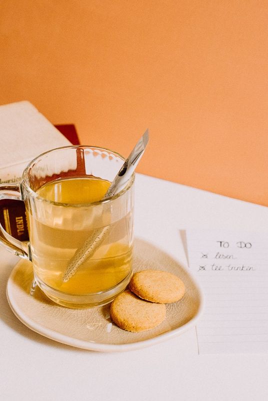 Vaso de té con stick, galletitas y una lista de tareas